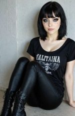 In this Candy AI Olivia Carter image, the AI generated character sits against a wall in a black outfit and leather boots, creating a bold pose.